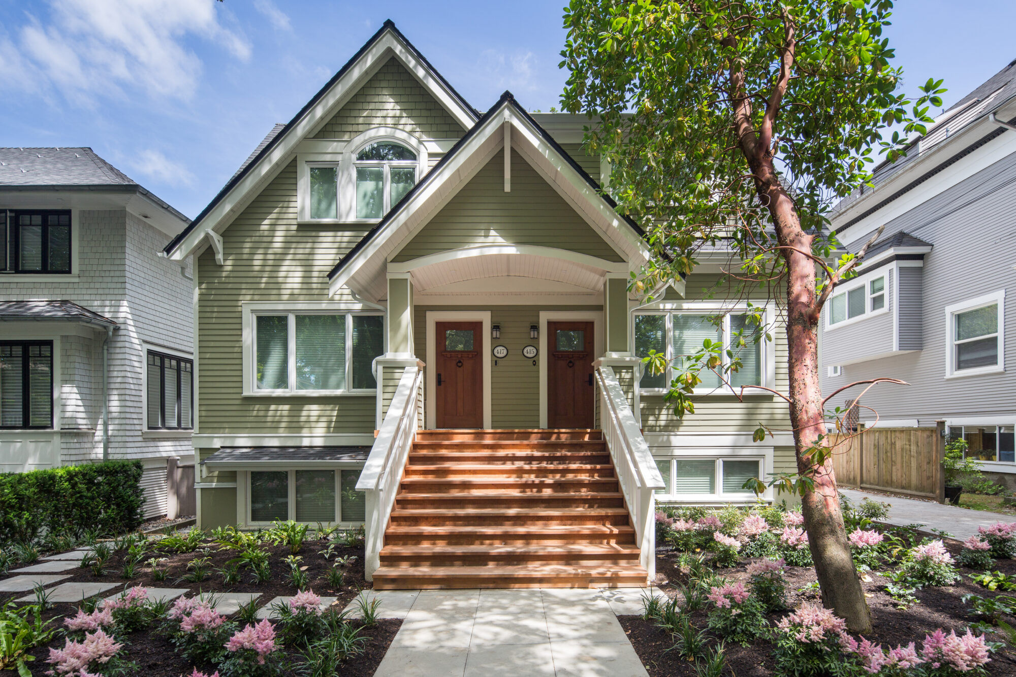 exterior of olive coloured traditional home with hardy board exterior walk up stairs to front doors of duplex.