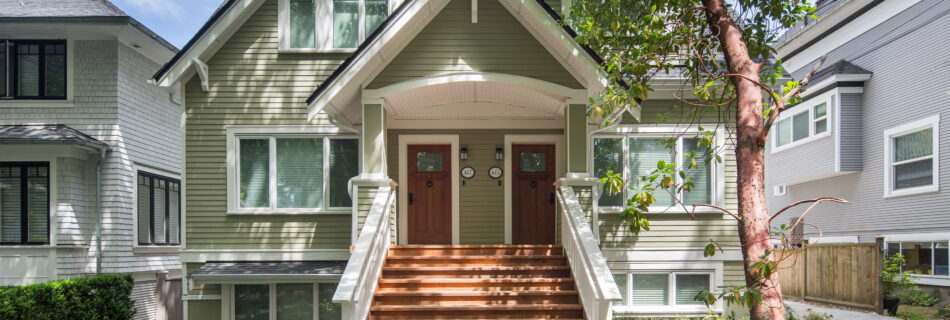 exterior of olive coloured traditional home with hardy board exterior walk up stairs to front doors of duplex.